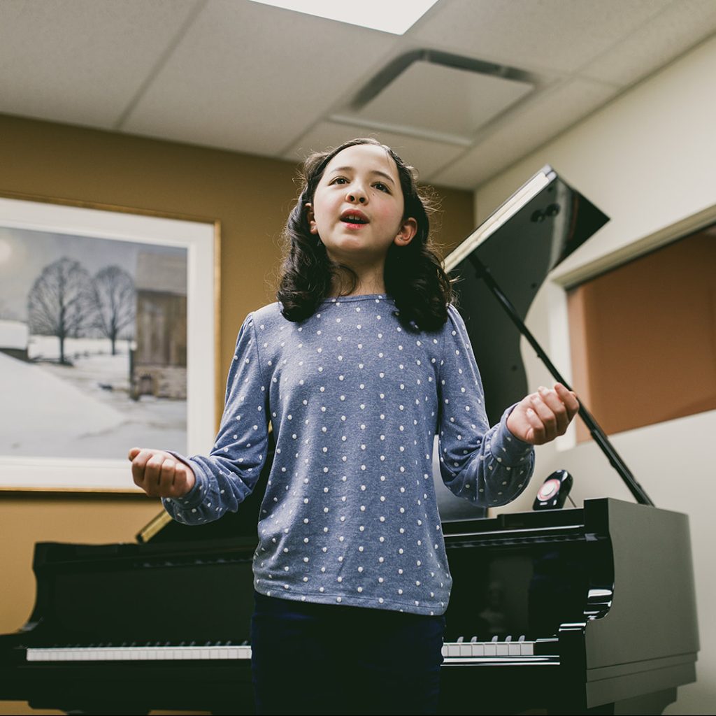 A young girl singing in a voice lesson
